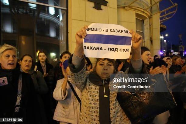 Female activist holds an anti-war poster as other protesters shout slogan during an unsanctioned protest rally at Arbat street on September 21 in...