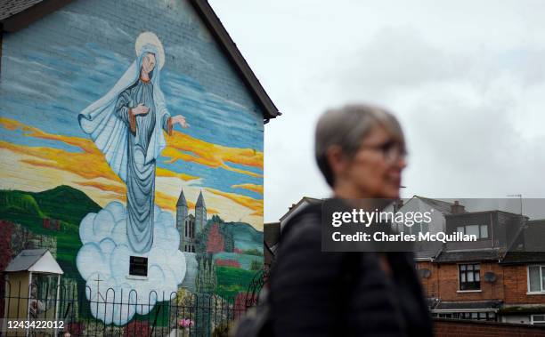 Woman walks past a Catholic religious mural on the day that the Northern Ireland census was released on September 22, 2022 in Belfast, Northern...