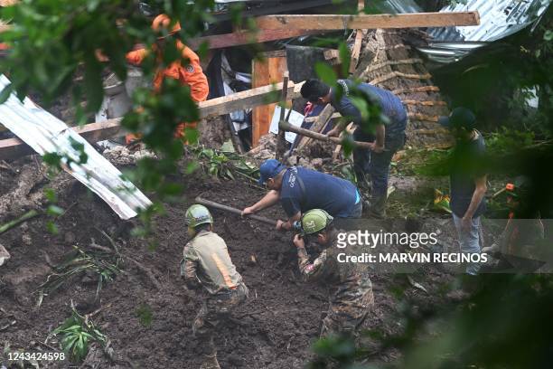 Salvadorian soldiers and rescuers try to recover the bodies of five people who died after a landslide in Huizucar, El Salvador, on September 22,...