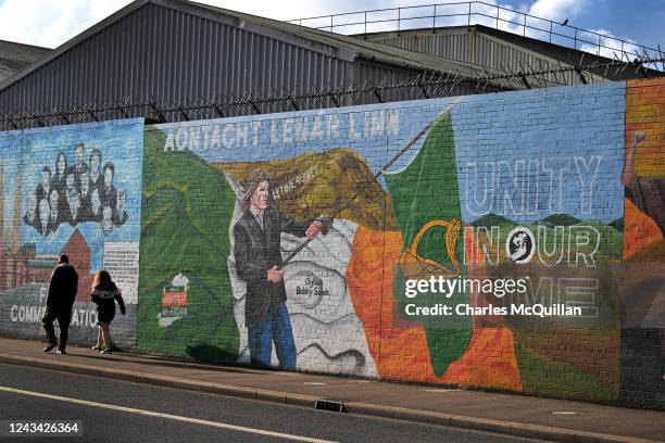 People walk past a mural calling for Irish unity on the day that the Northern Ireland census was released on September 22, 2022 in Belfast, Northern...