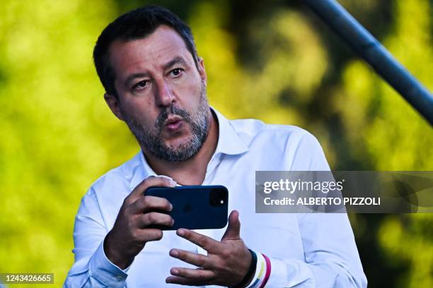 Lega leader Matteo Salvini holds his mobile phone as he prepares to step on stage on September 22, 2022 for a joint rally of Italy's right-wing...