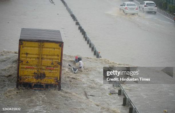Vehicles wade through a waterlogged stretch in heavy rain on the NH-48 service road near Narsinghpur village on September 22, 2022 in Gurugram,...