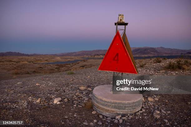 Disused fixed navigation beacon stands high above the level of Lake Mead, in the far distance, atop Sand Island, which is no longer an island, as...