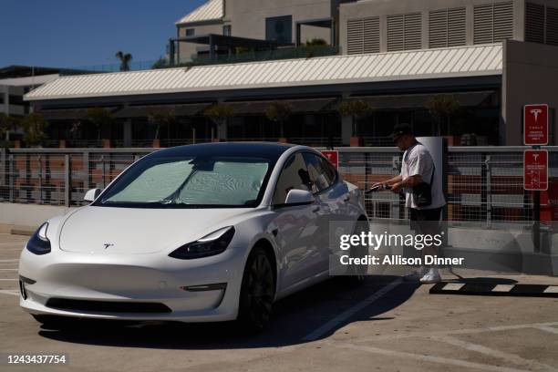 Man plugs his Tesla vehicle into a Tesla charging station on September 22, 2022 in Santa Monica, California. Tesla is recalling over 1 million...