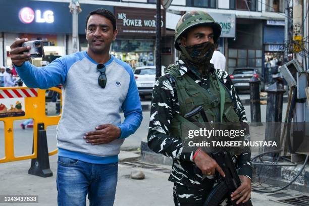 In this photograph taken on September 9 a tourist takes a selfie with an Indian paramilitary trooper standing guard along a street in Srinagar. -...