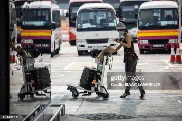 Woman walks to a bus at Hong Kong International Airport before going to hotel quarantine on September 23, 2022. - Hong Kong announced on September 23...