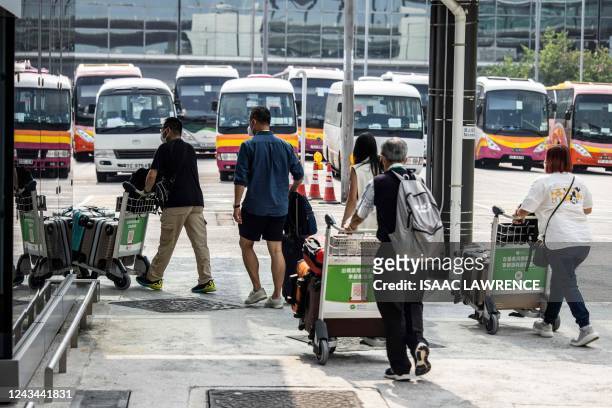 Travellers make their way to a bus at Hong Kong International Airport before going to hotel quarantine on September 23, 2022. - Hong Kong announced...