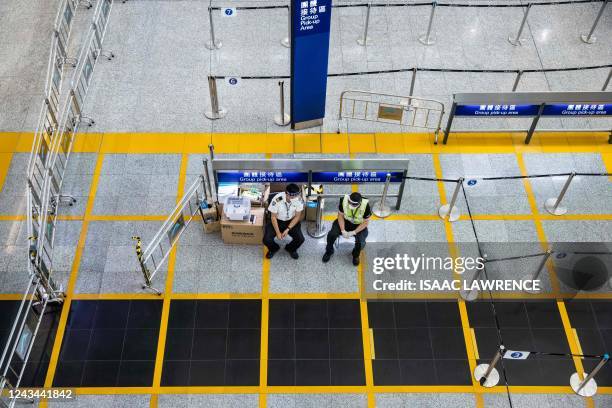 Workers wait for travellers to arrive at Hong Kong International Airport on September 23, 2022. - Hong Kong announced on September 23 it will end...