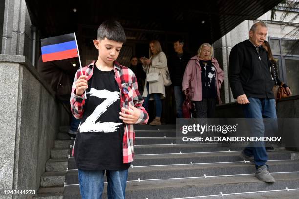 Boy wearing a T-shirt with the letter 'Z', the tactical insignia of Russian troops in Ukraine, and holding a flag of the self-proclaimed Donetsk...