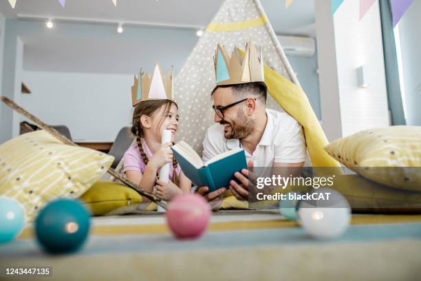 padre está leyendo un libro a la hija - fairy tale fotografías e imágenes de stock