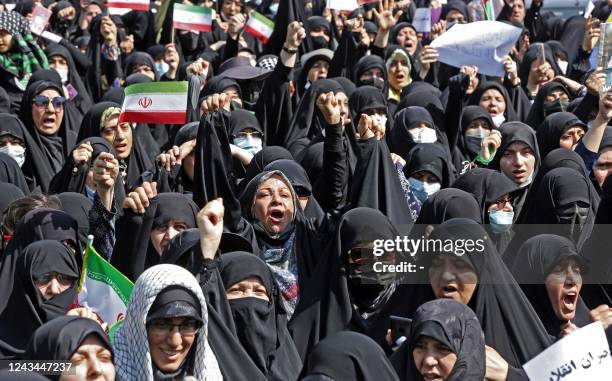 Iranians wave the national flag as they march during a pro-hijab rally in the capital Tehran on September 23, 2022. - Thousands of people marched...