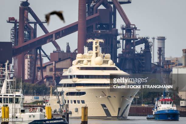 The super-yacht Dilbar is pulled past the Arcelor Mittal steelworks on the Weser river in Bremen on September 23, 2022 towards a dock after it had...