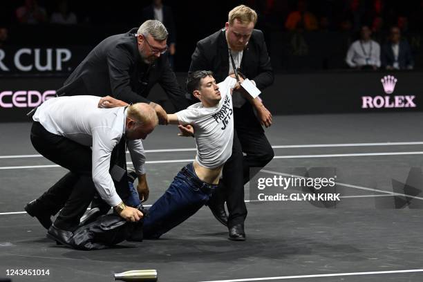 Protester is removed after invading the court, wearing a slogan 'End UK Private Jets' during the singles game between Greece's Stefanos Tsitsipas of...