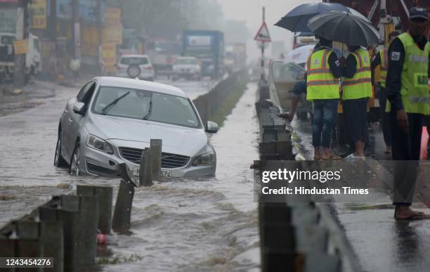 Car got stuck on a waterlogged road in heavy rain on NH-48 near the footover bridge, in Narshingpur village, on September 23, 2022 in Gurugram,...