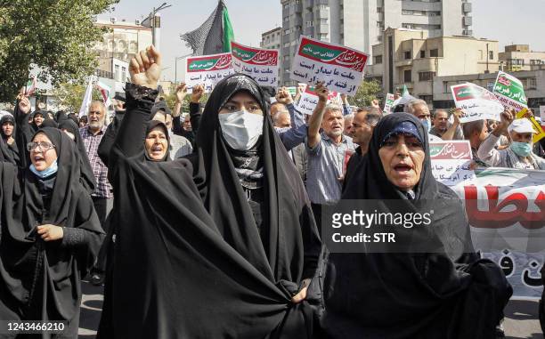 Women and men chant slogans as they march in a pro-hijab rally in Iran's capital Tehran on September 23, 2022. - Thousands of people marched through...