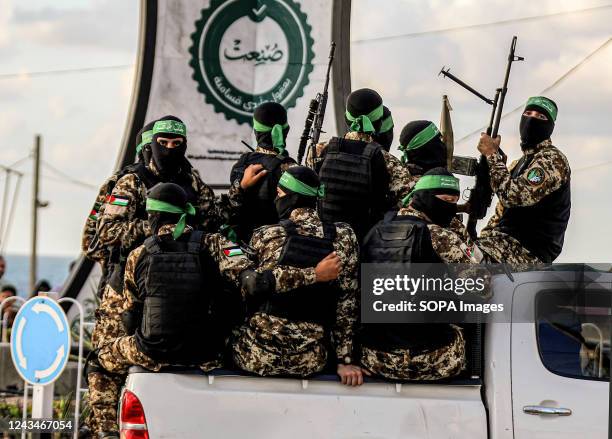 Members of the Izz al-Din al-Qassam Brigades, the military wing of the Islamic Movement of Hamas, are seen in the back of a pickup truck during the...