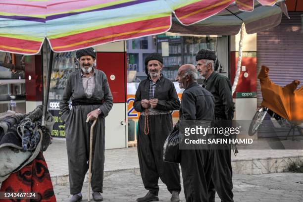 Iraqi Kurdish men dressed in traditional clothing stand along the side of a street in the Penjwen district, about 96 kilometres north of Iraq's...