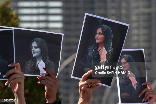 Women hold up signs depicting the image of 22-year-old Mahsa Amini, who died while in the custody of Iranian authorities, during a demonstration...