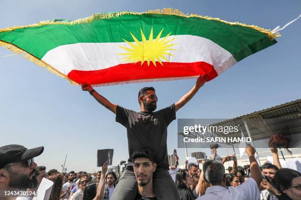 Man waves a Kurdish flag as he sits upon the shoulders of another during a demonstration denouncing the death of 22-year-old Mahsa Amini -- who died...