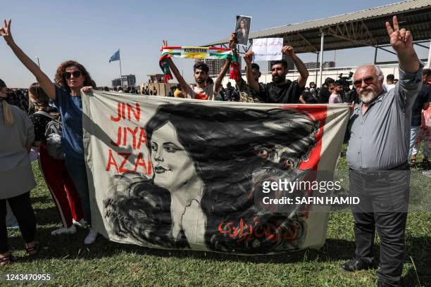 Man and a woman hold up a banner depicting the image of 22-year-old Mahsa Amini, who died while in the custody of Iranian authorities, during a...