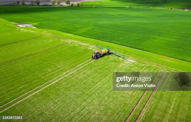 agriculture - tractor spraying pesticides in green field - spraying weeds stock pictures, royalty-free photos & images