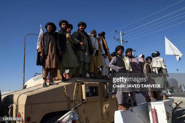 Afghan men climb atop vehicles to watch the motorcade carrying Bashar Noorzai , a warlord, and Taliban associate who was released by the US in a...