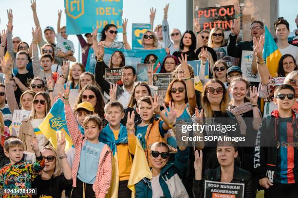 Ukrainian protesters hold placards and three fingers up in the air as a symbol of the Ukrainian National Emblem during an anti-war and...