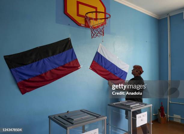 Woman hangs flags as people cast their votes in controversial referendums in Donetsk Oblast, Ukraine on September 24, 2022. Voting will run from...