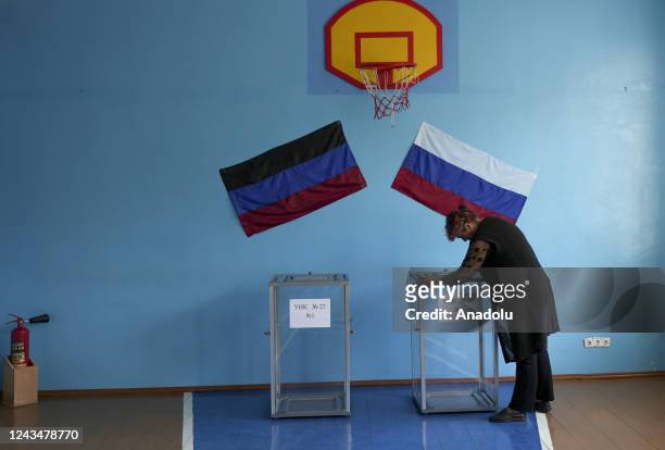 Woman hangs flags as people cast their votes in controversial referendums in Donetsk Oblast, Ukraine on September 24, 2022. Voting will run from...