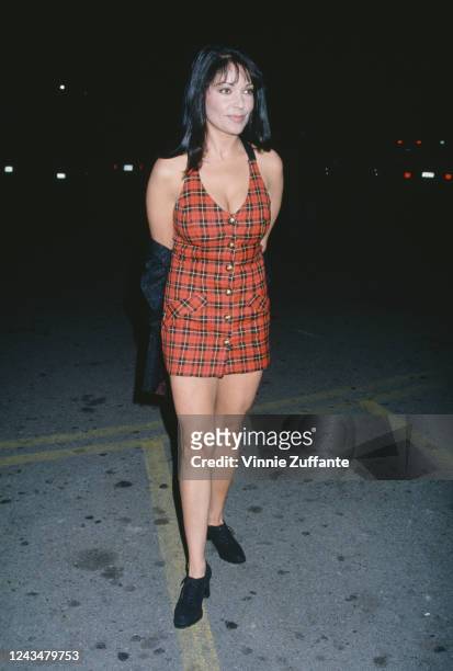 American singer and actress Apollonia Kotero, wearing a tartan minidress, attends the premiere of 'Dumb and Dumber', held at the Cinerama Dome...
