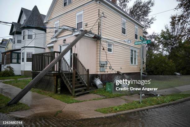 Downed power lines from winds from Post-Tropical Storm Fiona rest against a home on September 24, 2022 in Sydney, Nova Scotia on Cape Breton Island...