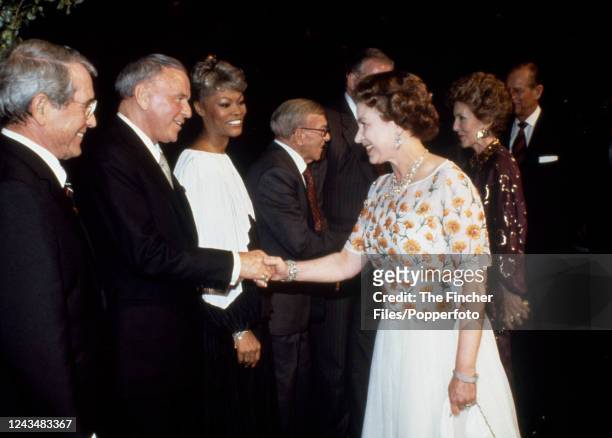Queen Elizabeth II shaking hands with American singer Frank Sinatra while attending a concert at the 20th Century Fox Studio given in the Queen's...
