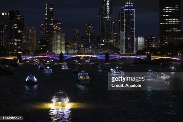 Fleet of 150 boats, decorated with lights in memory of Queen Elizabeth II, sail on the Thames river between Albert and Tower bridges in London,...