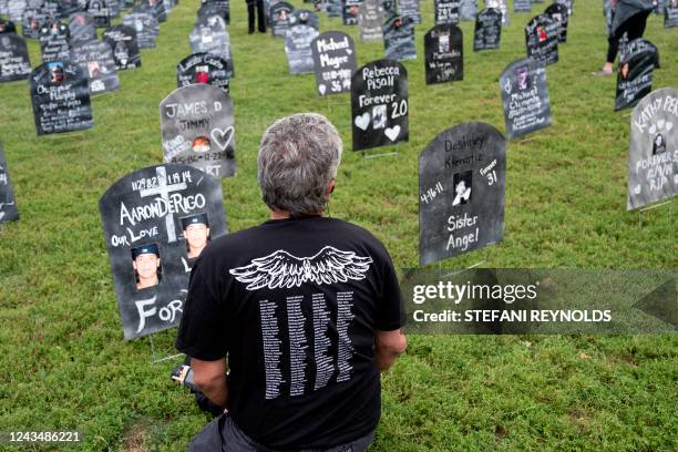 Person who lost a relative to a drug overdose sits among imitation graves set up by the Trail of Truth, near the US Capitol in Washington, DC, on...