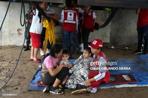 Woman and her two children is helped by a member of the Honduran red cross after the overflow of the Ulua river in El Progreso, Honduras, on...