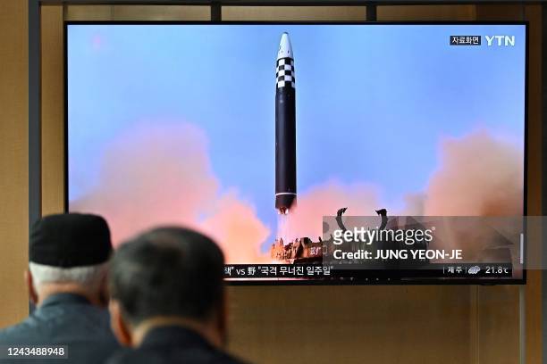 People watch a television screen showing a news broadcast with file footage of a North Korean missile test, at a railway station in Seoul on...