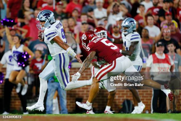 Quarterback Adrian Martinez of the Kansas State Wildcats stiff arms his way to a 15-yard touchdown against defensive back Billy Bowman Jr. #5 of the...