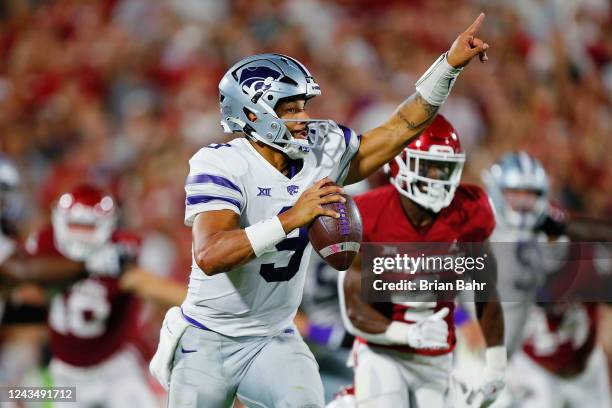 Quarterback Adrian Martinez of the Kansas State Wildcats signals to his receiver on the run against defensive back Jaden Davis of the Oklahoma...