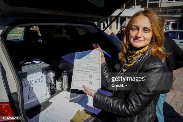 Woman shows her ballot for a referendum at a mobile voting station in Mariupol on September 25, 2022. - Western nations dismissed the referendums in...