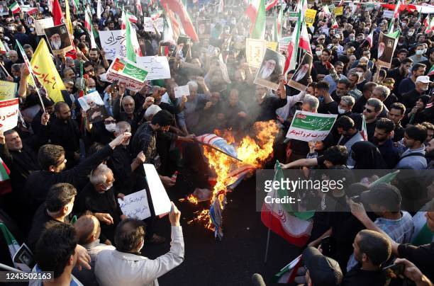 Iranian pro-government protesters burn flags of the US, Israel and Britain during a rally against the recent anti-government protests in Iran, in...