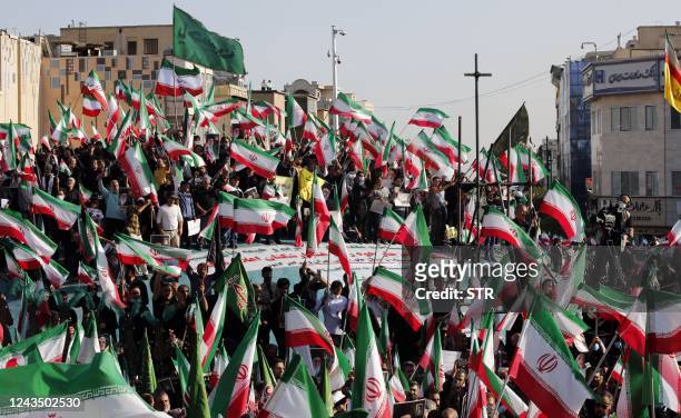 Iranian pro-government protesters wave their national flag during a rally against the recent anti-government protests in Iran, in Tehran, on...