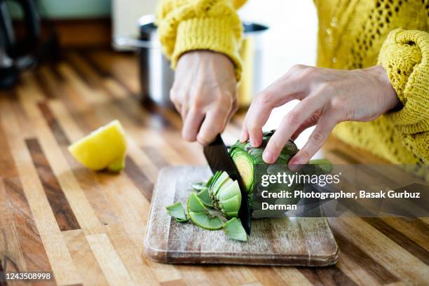 a woman preparing, cleaning, cutting, trimming off artichoke - artischocke stock-fotos und bilder