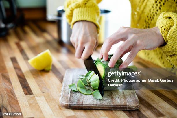 a woman preparing, cleaning, cutting, trimming off artichoke - artichoke stock pictures, royalty-free photos & images