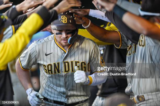 Brandon Drury of the San Diego Padres is congratulated in the dugout after hitting an eighth inning solo home run against the Colorado Rockies at...