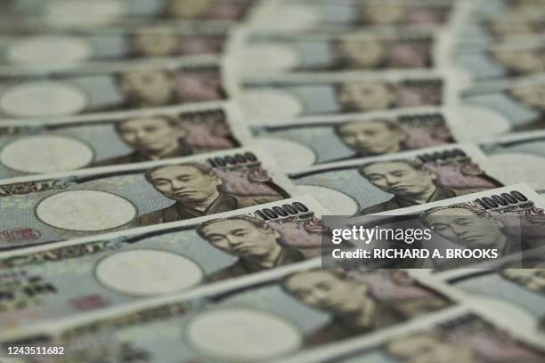 This photo illustration taken on September 24, 2022 shows Japanese 10,000 yen notes on display in Tokyo. - Japan's finance ministry on September 22...