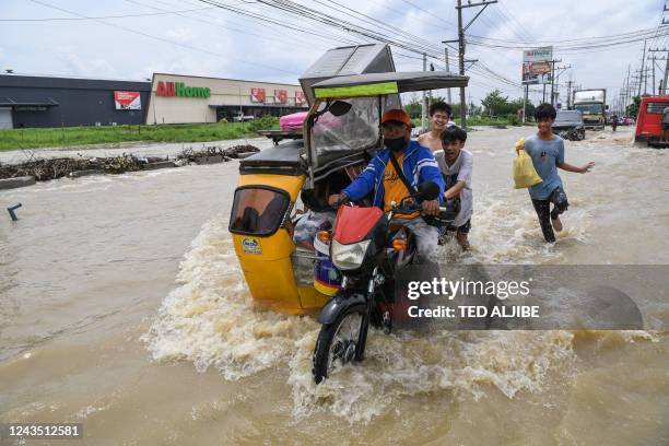Residents commute on a tricycle loaded with their belongings along a flooded highway while evacuating from their submerged homes in the aftermath of...