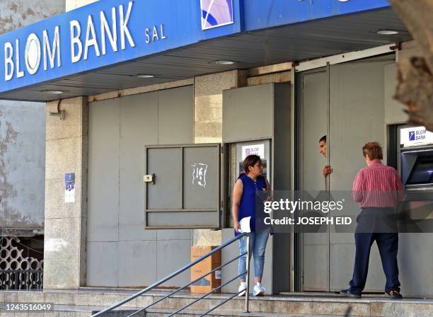 Lebanese depositors withdraw money from an ATM machine outside BLOM bank in Beirut on September 26, 2022 as banks partially re-opened following a...