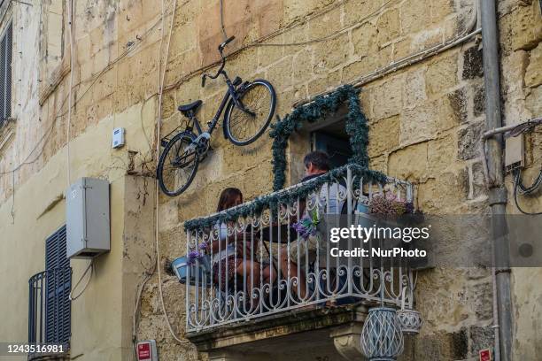 People enjoying their dinner on the balcony of the restaurant are seen in Rabat , Malta on 23 September 2022 The bicycle hanging on the wall over...