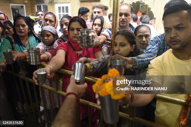 Hindu devotees hold cups of milk and water as they prepare to offer rituals on the occasion of the Navratri festival at the Mata Longa Wali Devi...