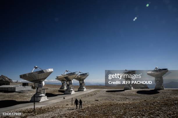 People walk past antennae, part of the NOEMA radio telescope on the « Plateau de Bure » in Saint-Etienne-en-Devoluy near the Superdevoluy resort, on...